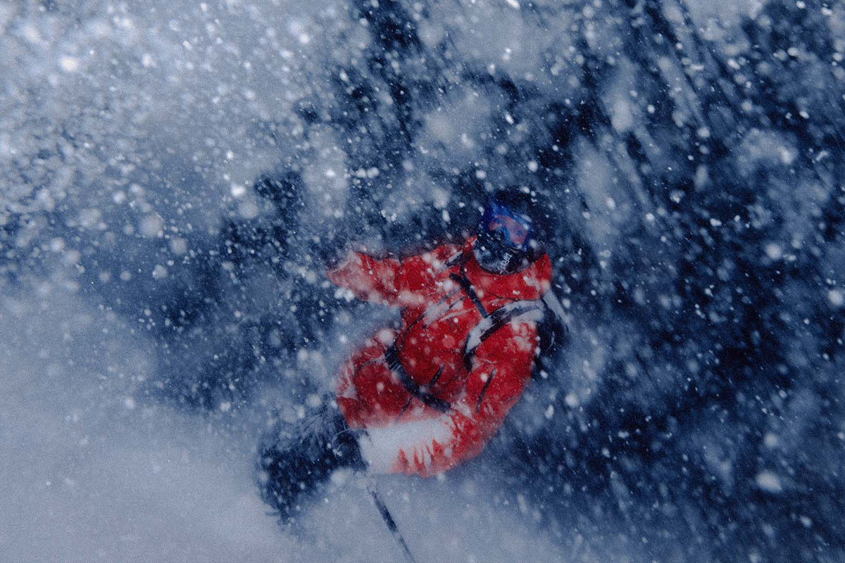 A skier in a red jacket in a cloud of powder snow