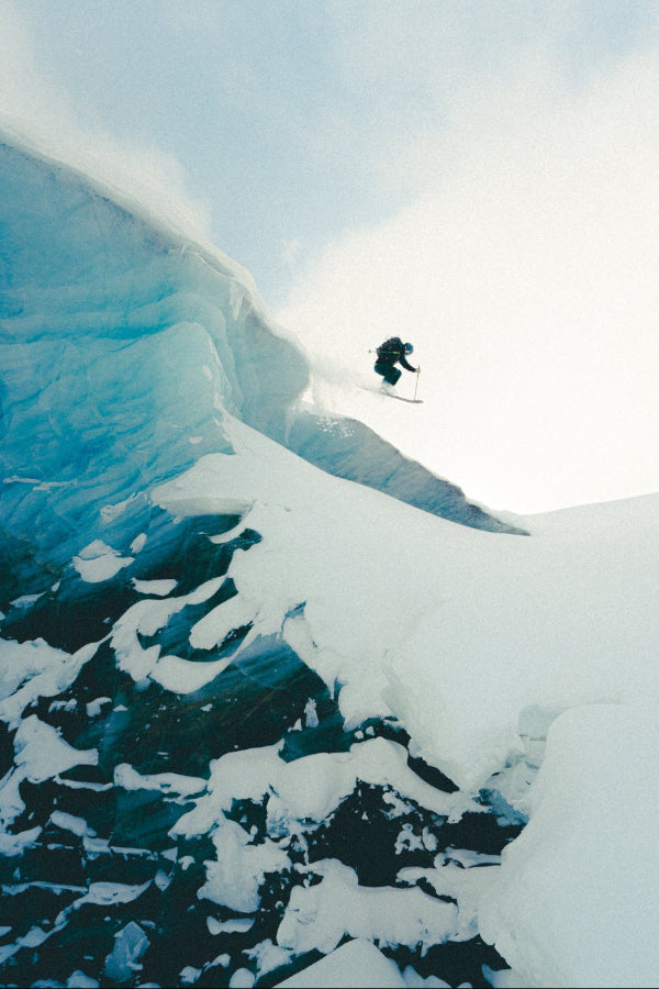 Person skiing down a snowy mountain with a glacier in the background