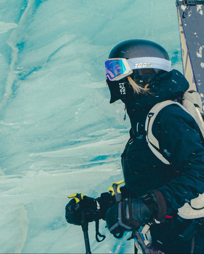 Person in winter gear with skis against a snowy background