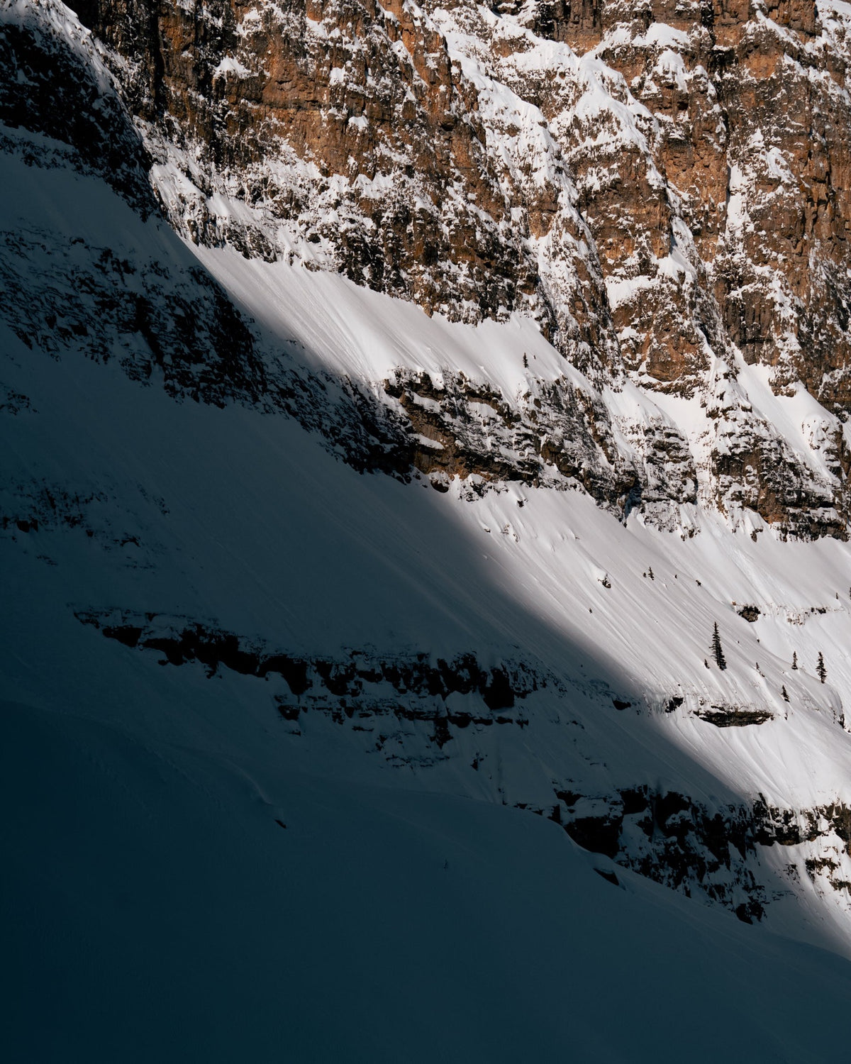 Sunlit snow below a rock wall